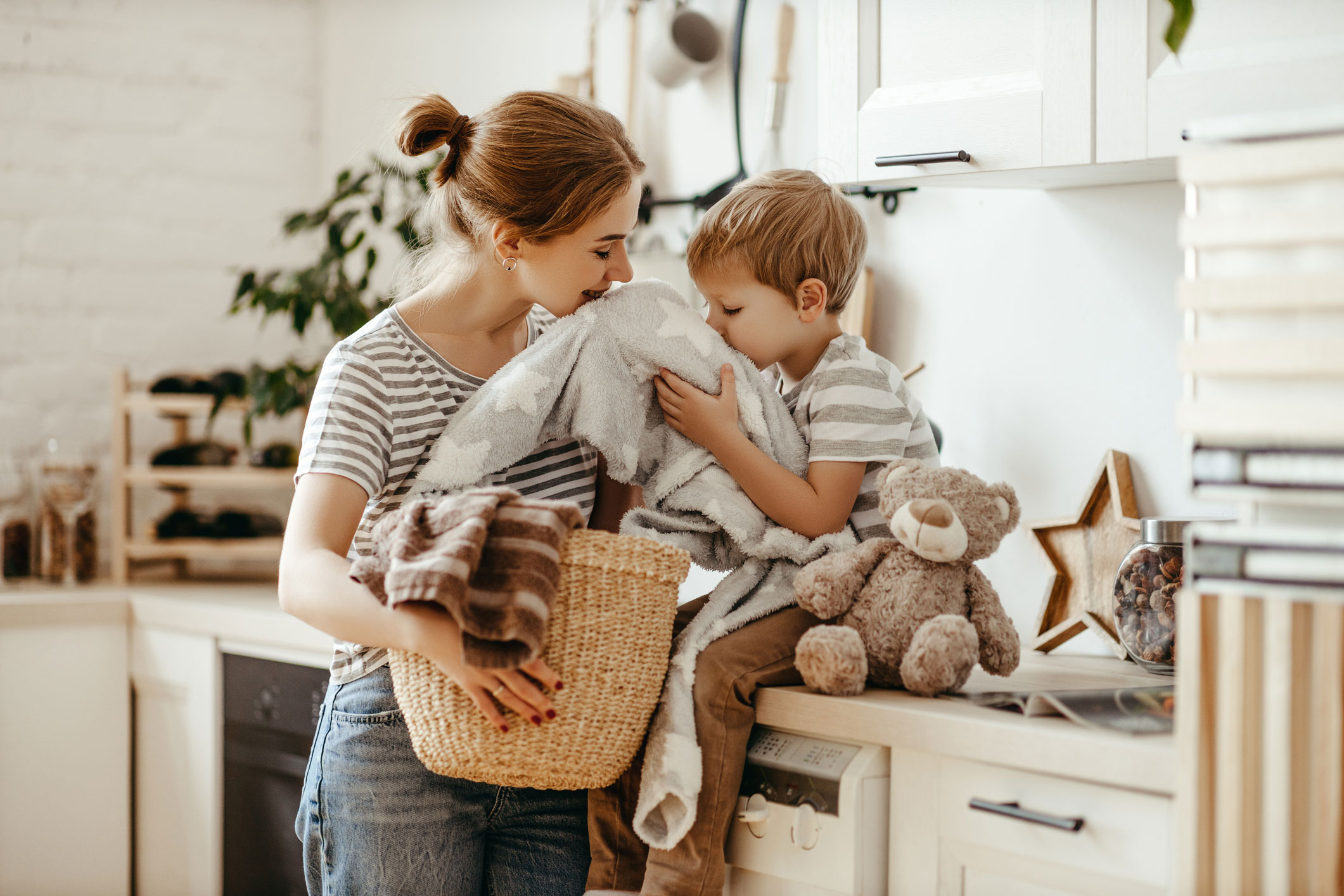 mother holding a laundry basket with young son and stuffed animal