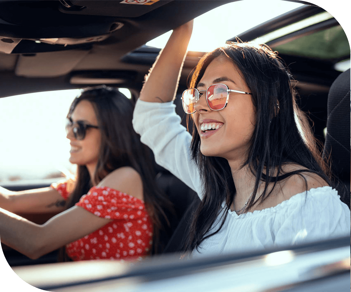 two people wearing sunglasses enjoying a car ride with the windows open on a sunny day 