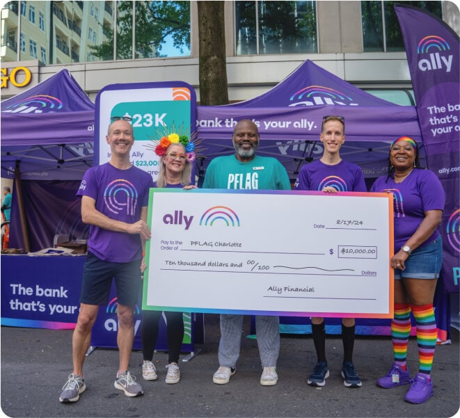 Smiling Ally Pride participants present a donation check to a PFLAG representative.