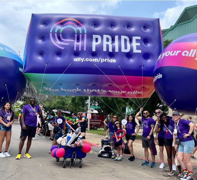 Cheerful parade participants pose with multicolored Ally Pride balloons.