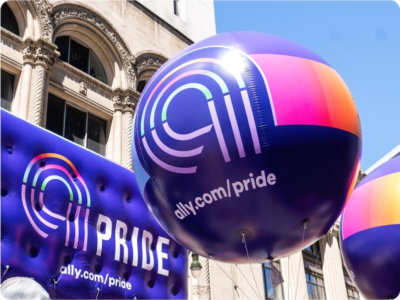 Purple Ally Pride balloons floating through the streets.