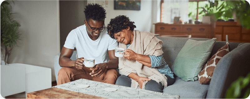 A grandmother and her grandson enjoying a cup of coffee together at home.