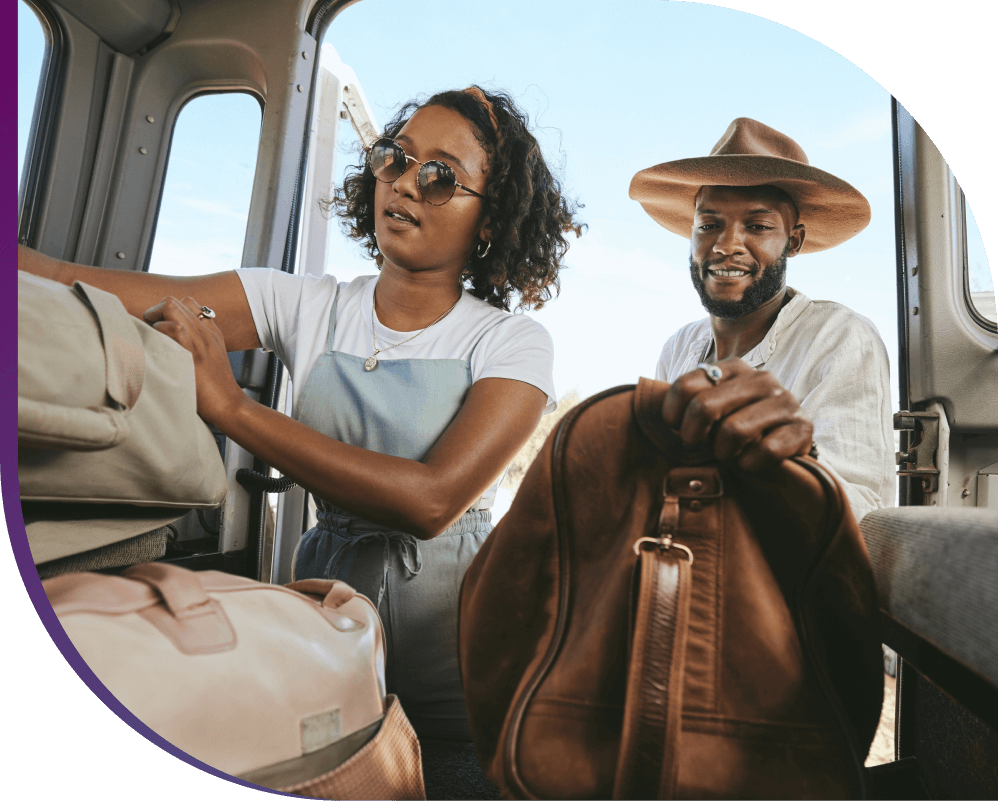 A couple excitedly packs their car with suitcases for a trip.