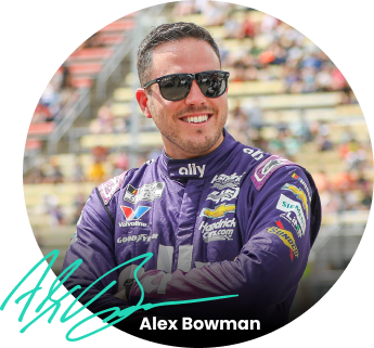 Alex Bowman, wearing sunglasses and the purple Ally firesuit, stares into the distance.