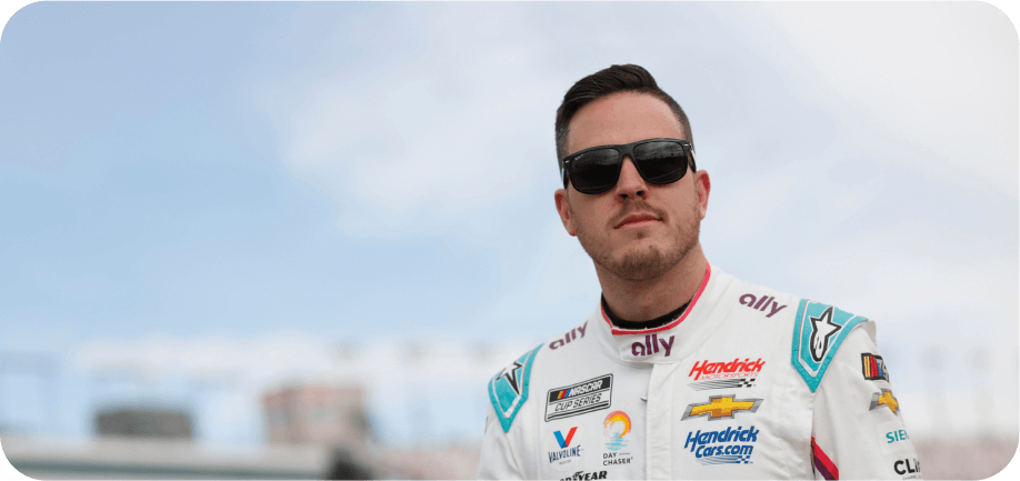 Alex Bowman, wearing sunglasses and the white Ally firesuit, stares into the distance​