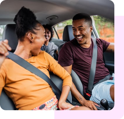 Three friends laugh together in a car. 