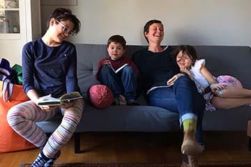  A mother laughs while sitting on a couch with her three children